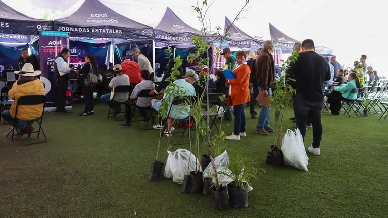 Outdoor garden festival with visitors walking among plants and vendor tents on a grass field